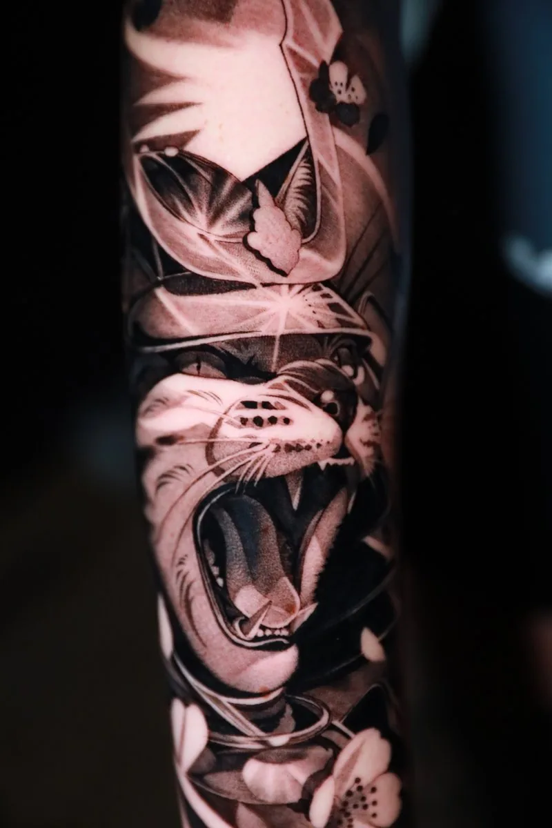 Black and grey panther with cherry blossoms on the forearm — Best of the Day at the Okanagan Tattoo Show 2026, tattooed by Alex Roze