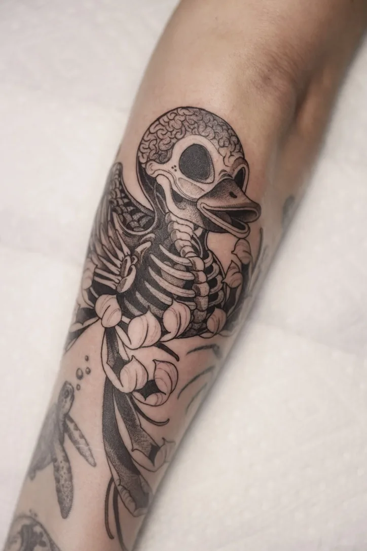 Skeleton duckling with exposed brain — black & grey tattoo by Alex Roze, Kelowna