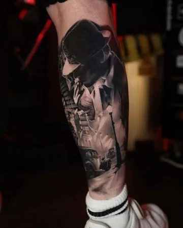 Film-noir figure in a hat leg — black & grey tattoo by Alex Roze, Kelowna