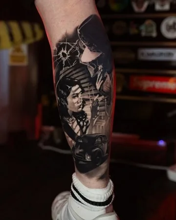 Film-noir woman and car scene leg — black & grey tattoo by Alex Roze, Kelowna