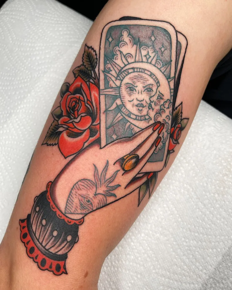 Tarot sun and moon cards held in a hand — traditional tattoo by Alex Roze, Kelowna