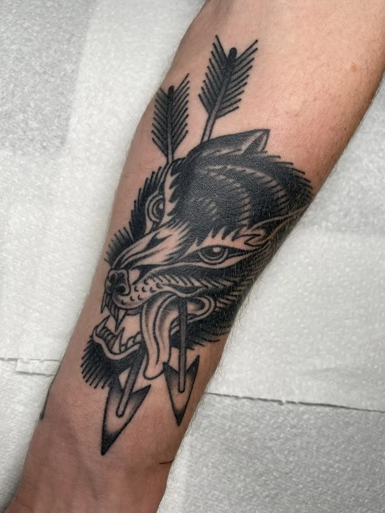 Wolf head pierced by arrows — traditional tattoo by Alex Roze, Kelowna