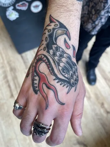 Stylized fish creature on the hand — traditional tattoo by Alex Roze, Kelowna