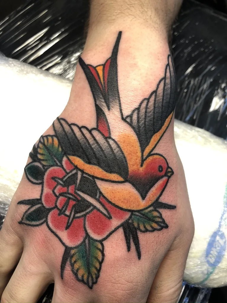 Swallow and flower on the hand — traditional tattoo by Alex Roze, Kelowna