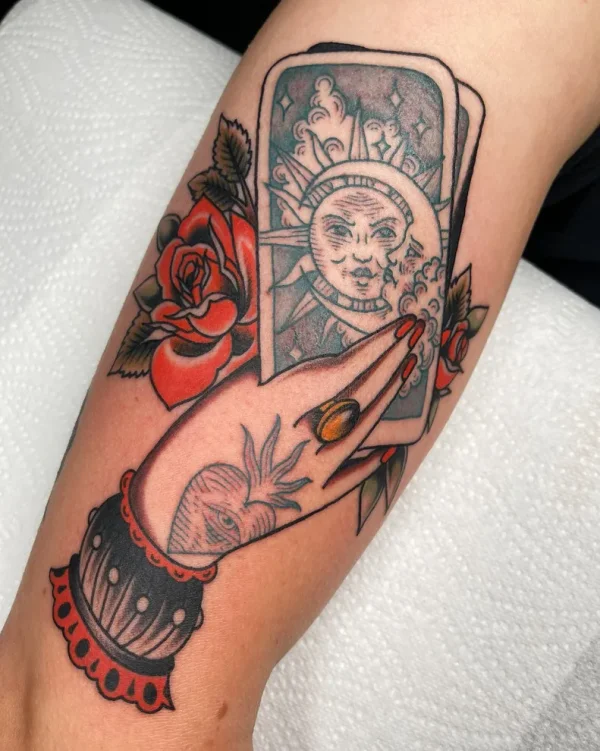 Tarot sun and moon cards held in a hand. Tattoo by Alex Roze.