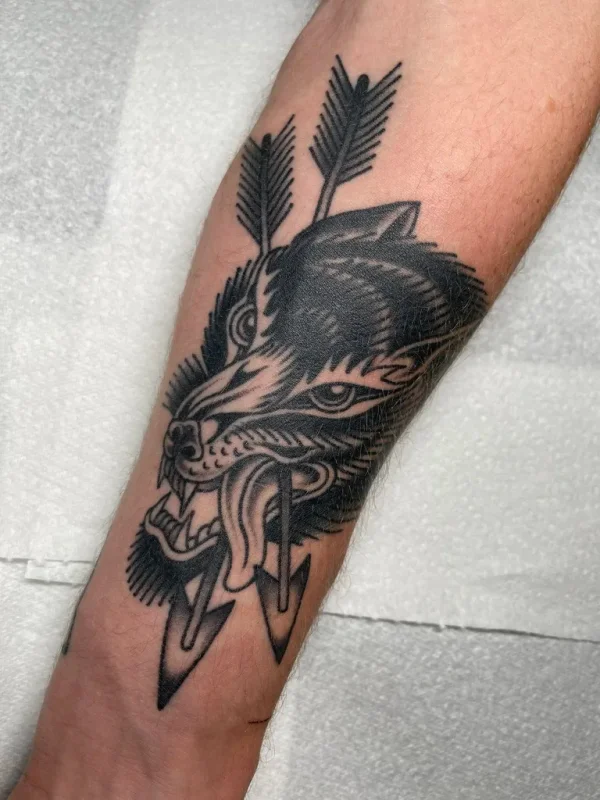 Wolf head pierced by arrows. Tattoo by Alex Roze.
