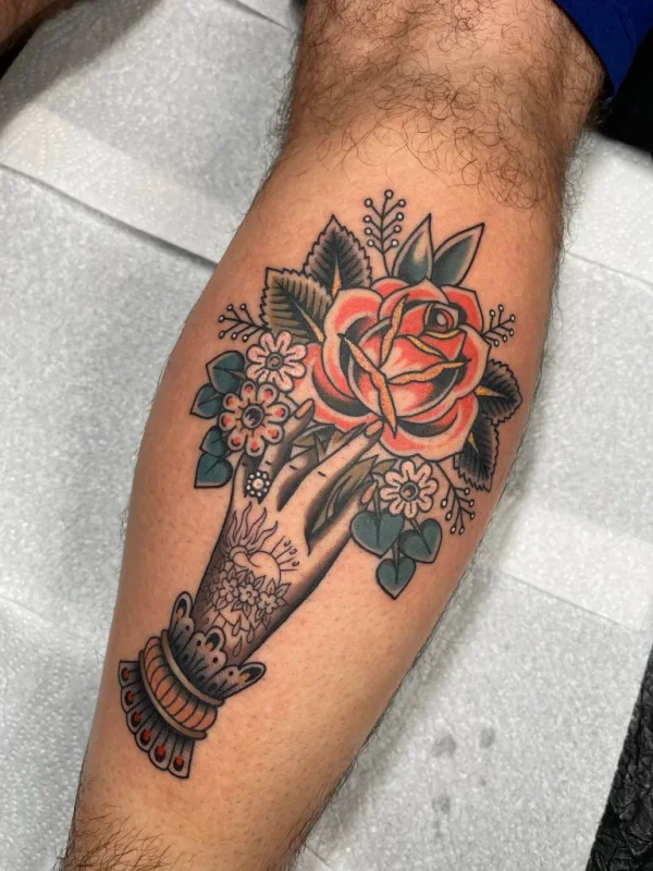 Hand holding a rose and flowers. Tattoo by Alex Roze.