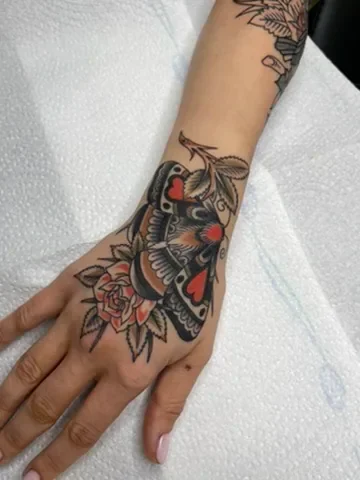 Moth and flowers across the hand. Tattoo by Alex Roze.