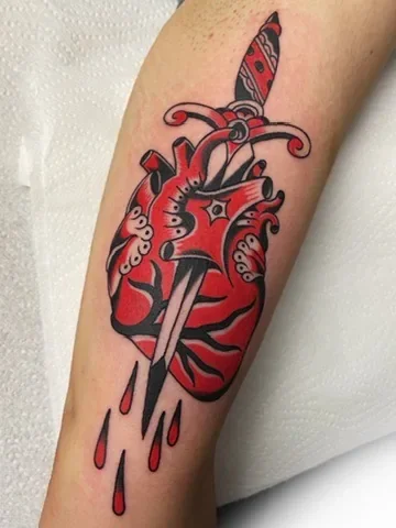 Red anatomical heart pierced by a dagger. Tattoo by Alex Roze.
