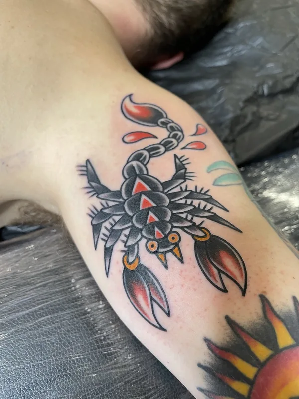 Traditional black and red scorpion tattoo on the upper arm. Tattoo by Alex Roze.